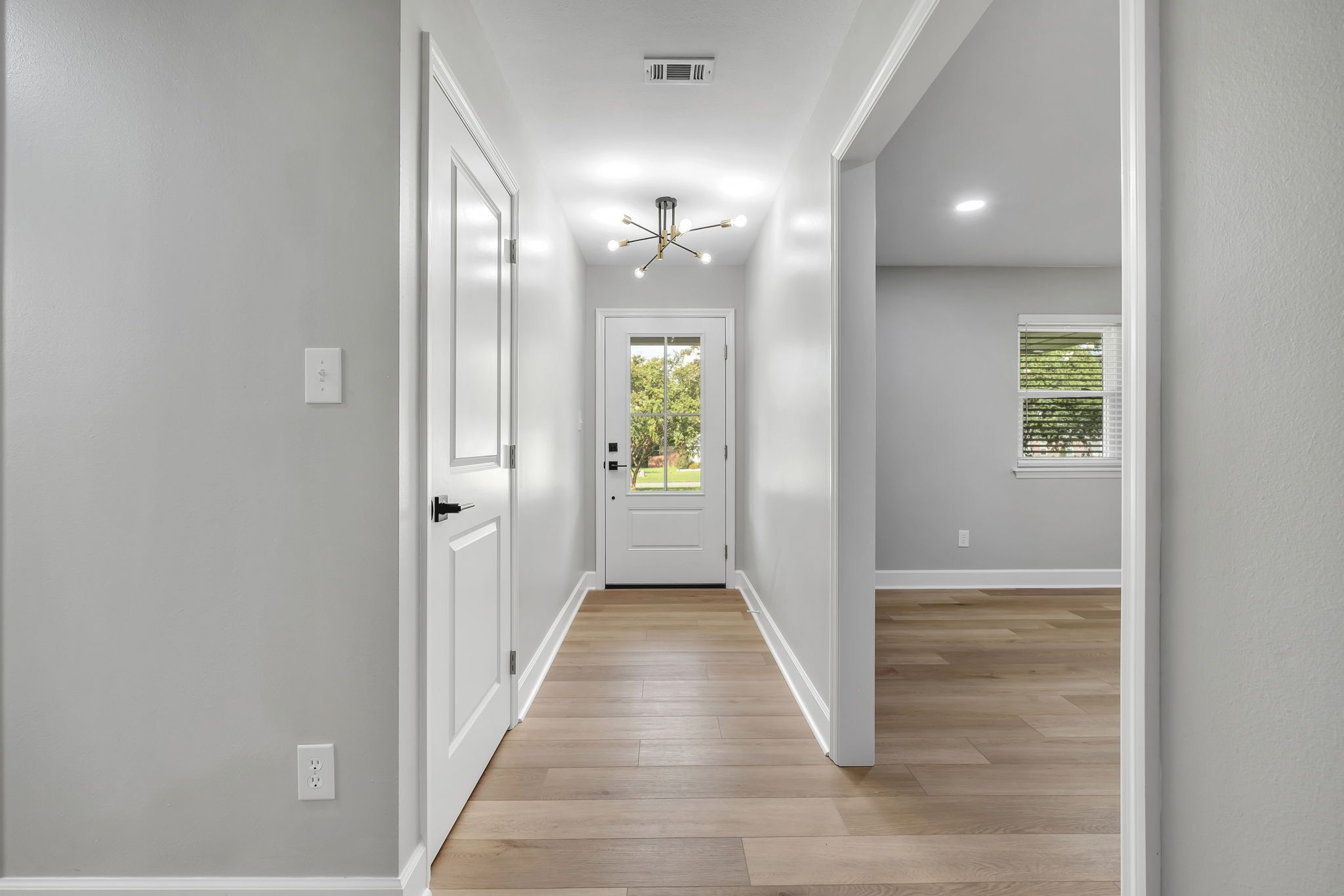 Entry hall under a brass fixture, looking out the glass front door to the lawn