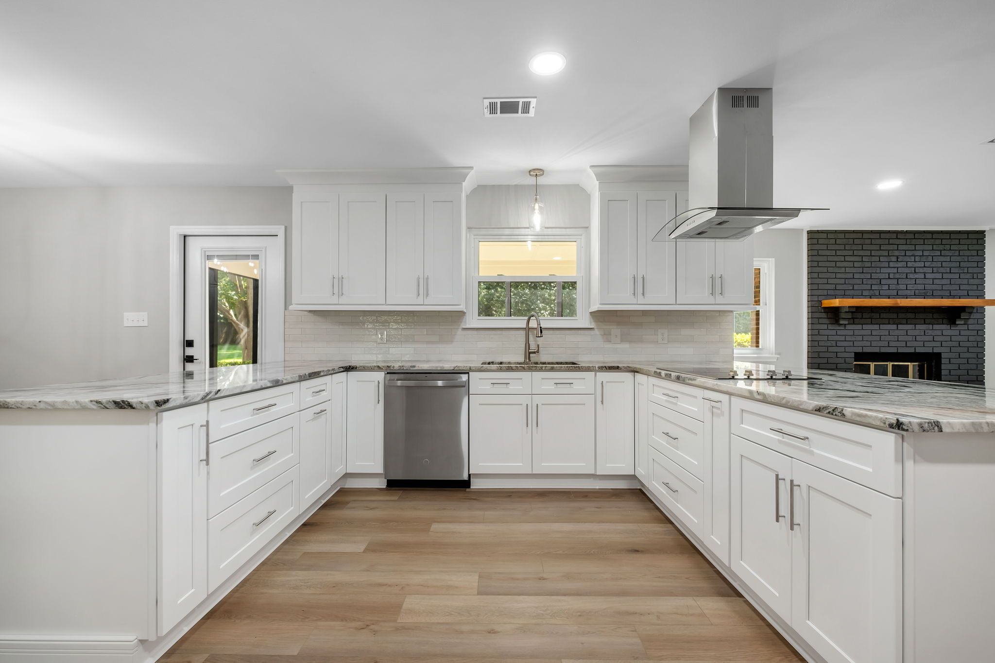 Remodeled kitchen with white shaker cabinetry, granite counters, an island vent hood, and stainless appliances